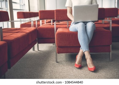 Female using modern gadget while sitting on cozy couch in lounge zone