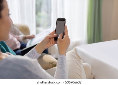 Female Using Smart Phone with Both Hands, with Cosy Home Background - Shutterstock ID 536906632