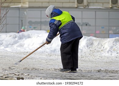 A Female Utility Worker Clears Snow From The Sidewalk