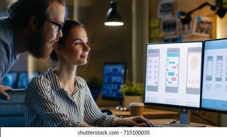 Female UX Architect Has Discussion with Male Design Engineer, They Work on Mobile Application Late at Night, She Drinks Coffee. In the Background Wall with Project Sticky Notes. - Shutterstock ID 715100035
