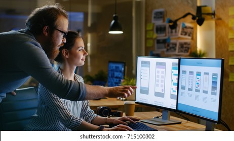 Female UX Architect Has Discussion with Male Design Engineer, They Work on Mobile Application Late at Night, She Drinks Coffee. In the Background Wall with Project Sticky Notes. - Shutterstock ID 715100302