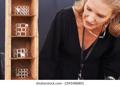 Female vendor at a crafts fair in her booth selling handmade artisan jewelry, looking at the tower of bracelets - Powered by Shutterstock