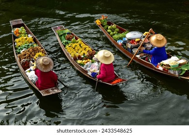 Female vendors on their boat(sampan) in narrow canals for sale their products such as fruits,food or souvenir in   "Damnoen Saduak Floating market" the most famous floating market in Thailand. - Powered by Shutterstock