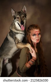Female viking  with painted face and grey wolf on brown background. Fantasy portrait of warrior girl