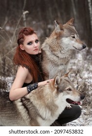 Female viking in warrior dress with two wolves in winter. Fantasy portrait of woman in cosplay dress