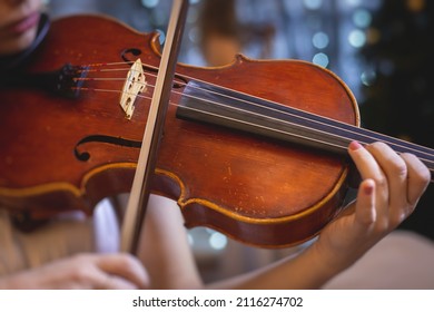 Female Violin Player, Fiddler Violinist With A Bow Performing Music On Stage During Concert With Orchestra And Musical Band In The Background