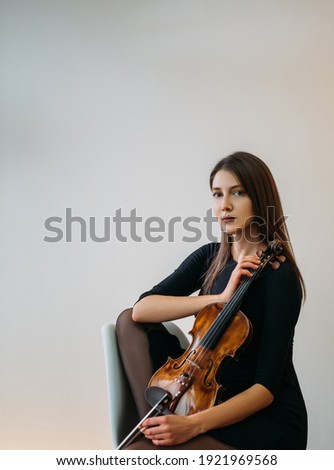 Female violinist portrait. Studio shooting. Classic music. Musician player. Artist hobby. Elegant calm woman posing with violin in hands isolated neutral background.