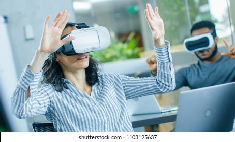 Female Virtual Reality Engineer/ Developer Wearing Virtual Reality Headset Creates Content With Her Colleagues. Creative Young People Work on the Augmented & Mixed Reality Project.