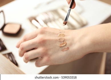 Female visagiste applying cosmetics onto hand