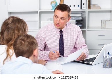 Female Visitor And Her Teenage Son Consulting Smiling School Teacher