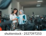 female visitor and saleswoman chatting about a new motorcycle while holding a brochure in a showroom