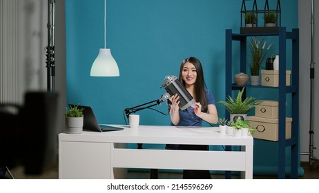 Female vlogger doing light recommentation on camera in studio, recording live podcast for social media audience. Blogger using studio lighting equipment to do product review on channel stream.