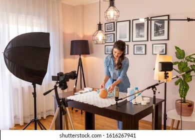 Female vlogger filming video about changing newborn baby clothes as part of online prenatal classes course; female influencer recording tutorial about newborn baby care
