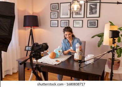 Female vlogger filming video about baby bottle milk preparation and heating in an household appliance as part of online prenatal classes course