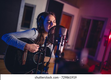 Female Vocal Artist Singing In A Recording Studio With Guitar. Woman Singer Singing A Song And Playing Guitar.