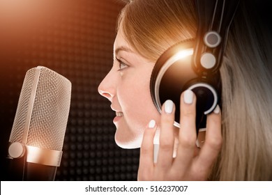 Female Voice Talent in Recording Studio. Girl Recording Voice Over For Radio Commercial. Young Girl in Her 20s and the Shiny Metallic Pro Microphone.