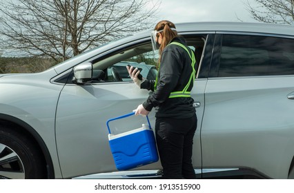 A Female Volunteer Assists A Senior Citizen At A COVID-19 Drive Thru Testing Site. 