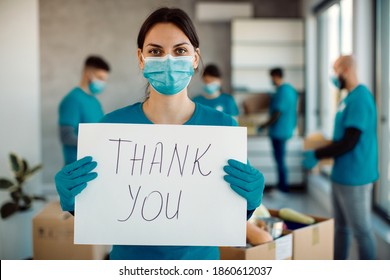 Female volunteer feeling grateful for charity donations and holding a placard with 'thank you' inscription while looking at camera. - Powered by Shutterstock