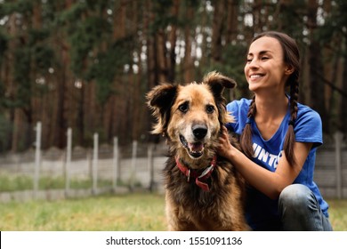 Female Volunteer With Homeless Dog At Animal Shelter Outdoors