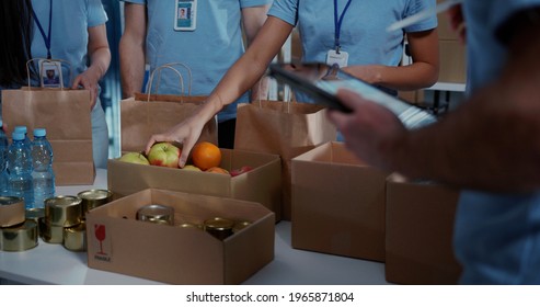 Female Volunteer Preparing Free Food Delivery For Poor People. As Charity Workers And Members Of The Community Work Together.