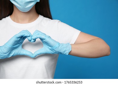 Female volunteer in protective mask and gloves showing heart gesture on blue background, closeup. Aid during coronavirus quarantine - Shutterstock ID 1765336253