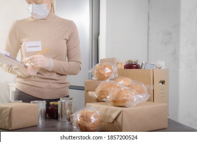 Female Volunteer Working In Food Bank Warehouse. Woman Is Sorting Food. Helping Poor And Needy People. Donation Concept.