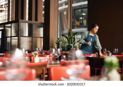 Female waitress setting tables in restaurant 