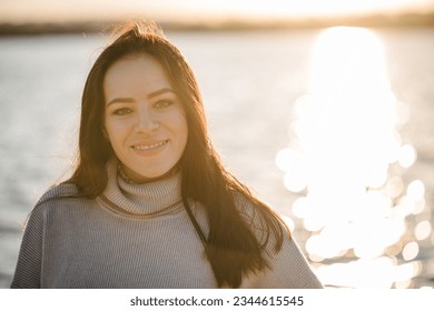 Female walk on sand near lake in park with sunlight. Portrait woman or mom on beach of nature. Family spending time at sunset on vacation. Concept of autumn holiday. Spring mood photo. Autumn girl