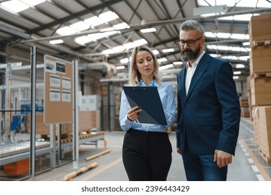 Female warehouse manager talking with logistics employee in warehouse, planning transport of products, goods, talking shipping process. - Powered by Shutterstock