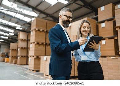 Female warehouse manager talking with logistics employee in warehouse, planning transport of products, goods, talking shipping process. - Powered by Shutterstock