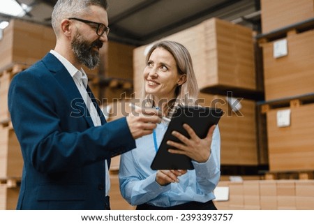 Female warehouse manager talking with logistics employee in warehouse, planning transport of products, goods, talking shipping process.