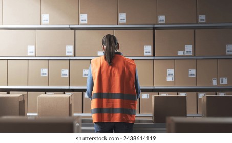 Female warehouse worker checking boxes on the conveyor belt, back view - Powered by Shutterstock