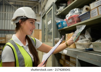 Female Warehouse Worker Counting Items In An Industrial Warehouse On The Factory's Mezzanine Floor. Which Is A Storage For Small And Light Electronic Parts.