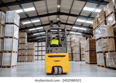 Female warehouse worker driving forklift. Warehouse worker pricking, preparing products for shipmennt, delivery, checking stock in warehouse. - Powered by Shutterstock