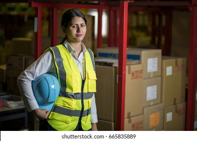 Female Warehouse Worker With Helmet And Safety Vest. 