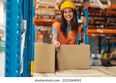 A female warehouse worker wearing a hard hat and safety vest is smiling while handling a cardboard box in a large industrial storage facility, reflecting efficiency and positivity. - Powered by Shutterstock