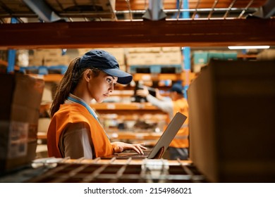 Female warehouse worker working on laptop at storage compartment.  - Powered by Shutterstock