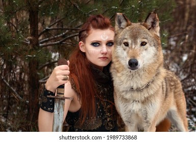 Female warrior with painted face and braided hair with sword in hand hugging wolf