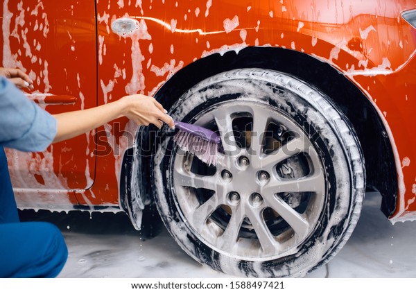 Female washer\
with brush cleans wheel, car\
wash