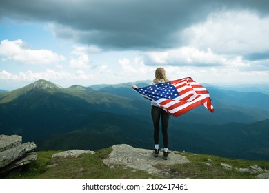 Female is waving American flag on top of mountain at sky background, celebrating independence day - Powered by Shutterstock