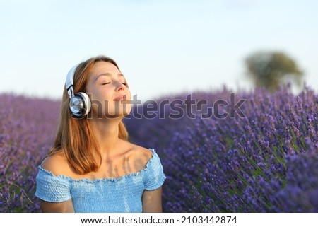 Female wearing headphones breathing fresh air listening to music in a lavender field