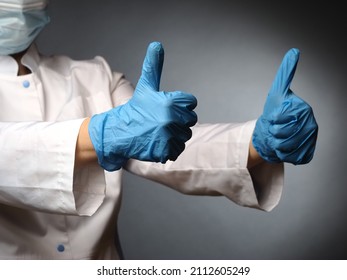 Female Wearing Mask Doctor's Hands In Nitrile Blue Gloves Show The Test Okay Thumbs Up