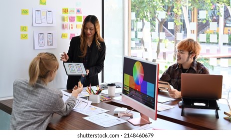Female website designer showing user interface design on digital tablet to creative team at office presentation. - Shutterstock ID 2148460679