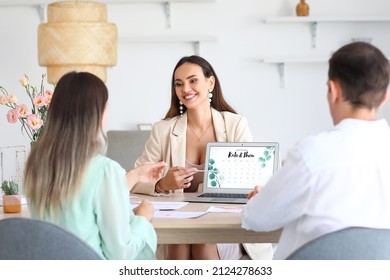 Female wedding planner discussing ceremony with clients in office - Shutterstock ID 2124278633