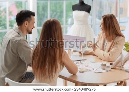 Female wedding planner working with couple in office