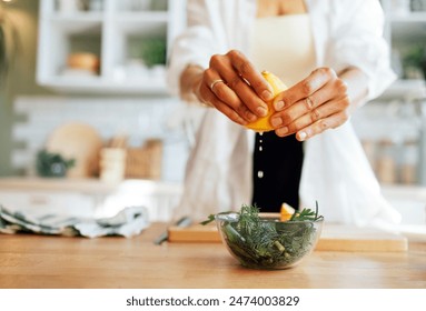 A female well-groomed hands with a neat manicure, squeezing lemon juice into a glass bowl with salad. Healthy food. Fresh green salad with arugula, onion and parsley. A young woman cooks in kitchen. - Powered by Shutterstock