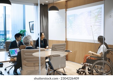 Female wheelchair user is giving a presentation to her team members