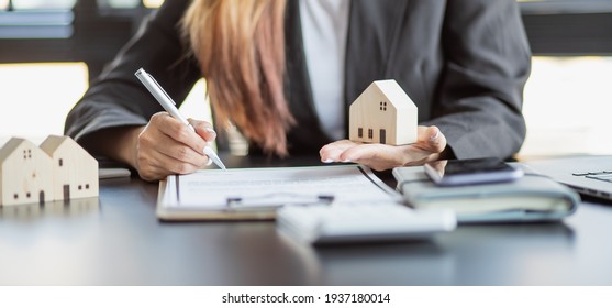Female woman hands holding home model, small miniature white toy house. Mortgage property insurance dream moving home and real estate concept - Shutterstock ID 1937180014