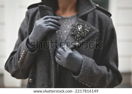 Female woolen warm gray double breasted coat and leather gloves. Stylish details of fashionista. Woman fashion outerwear