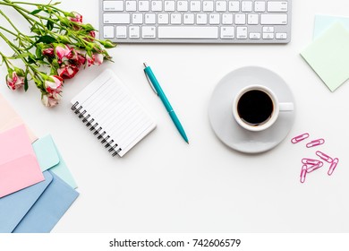 female work space with flowers, coffee and notebook white background top view mockup